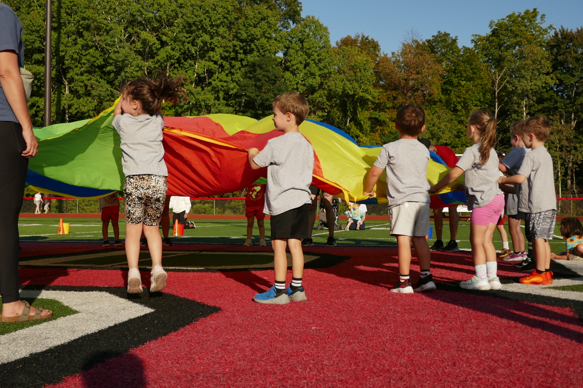 Children holding on to rainbow parachute